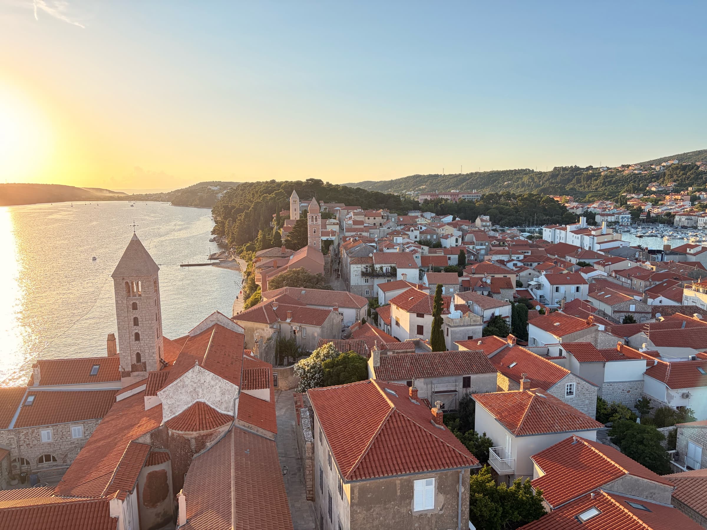 Golden sunset over the rooftops and bell towers of Rab's historic core.